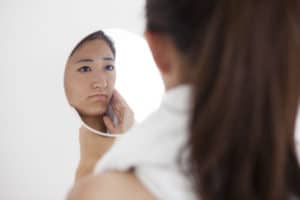 鏡で肌のくすみを確認する女性